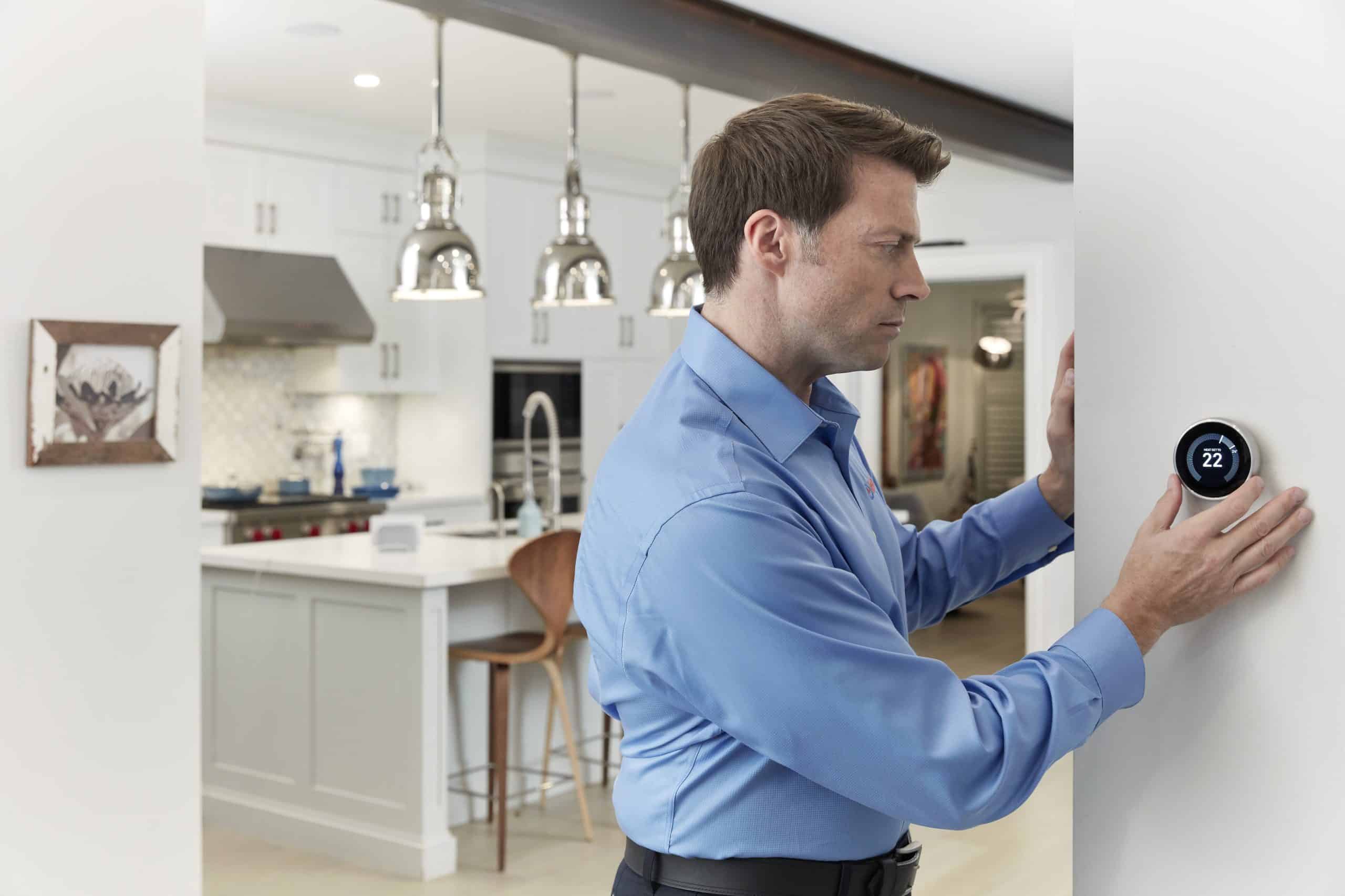 Male configuring smart thermostat at home
